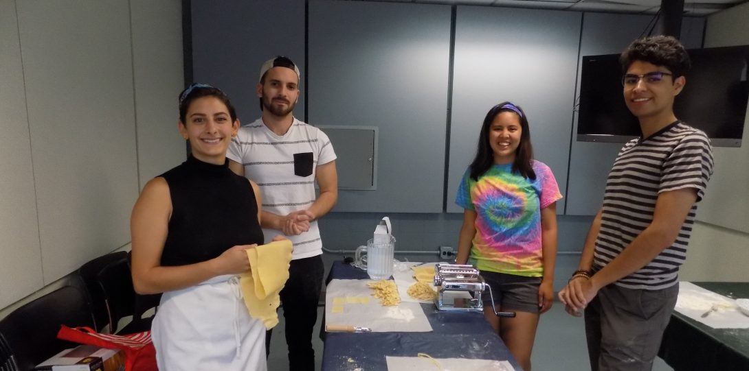 a female UIC faculty member poses with a mixed group of students and their pasta